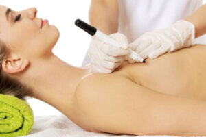 A woman getting her breast waxed by an esthetician.